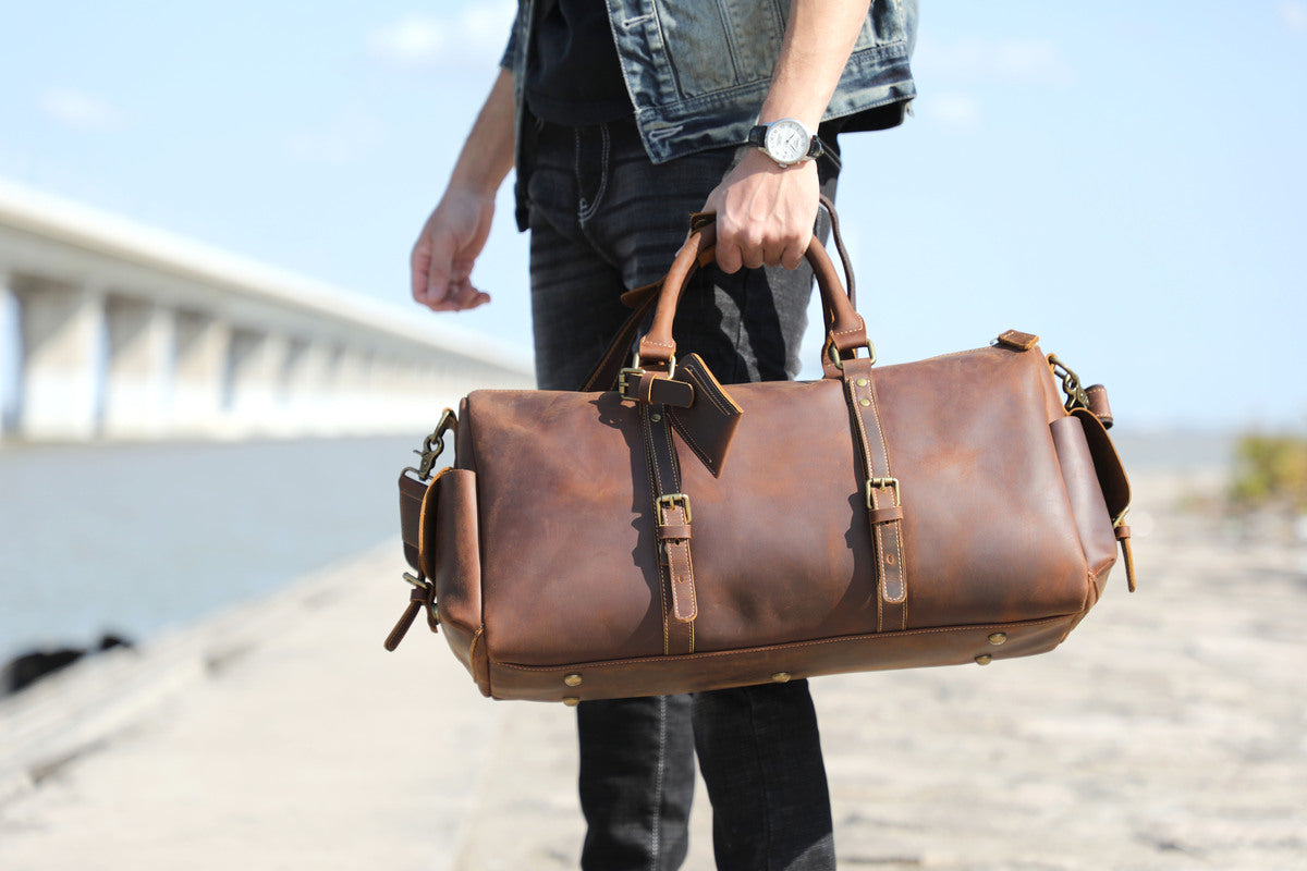 man holding in his hand a coffee leather duffle bag