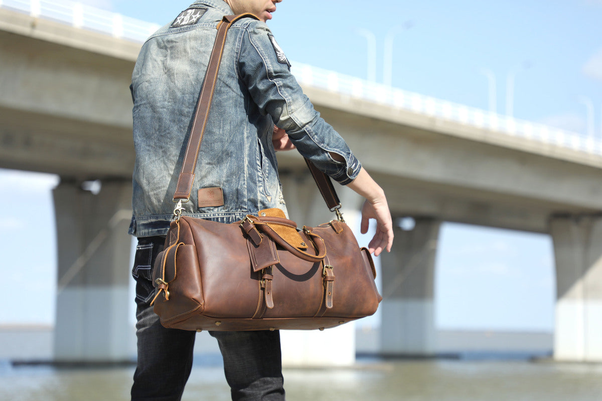 man wandering near a wearing wearing over his shoulder a travel leather duffle