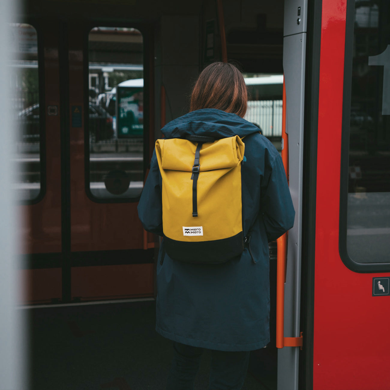 femme marchant dans une forêt avec un sac à dos urbain roll top en matériaux recyclés jaunes mero mero