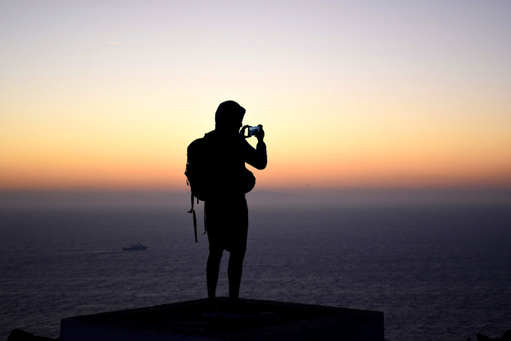 randonneur capturant le coucher de soleil avec son smartphone