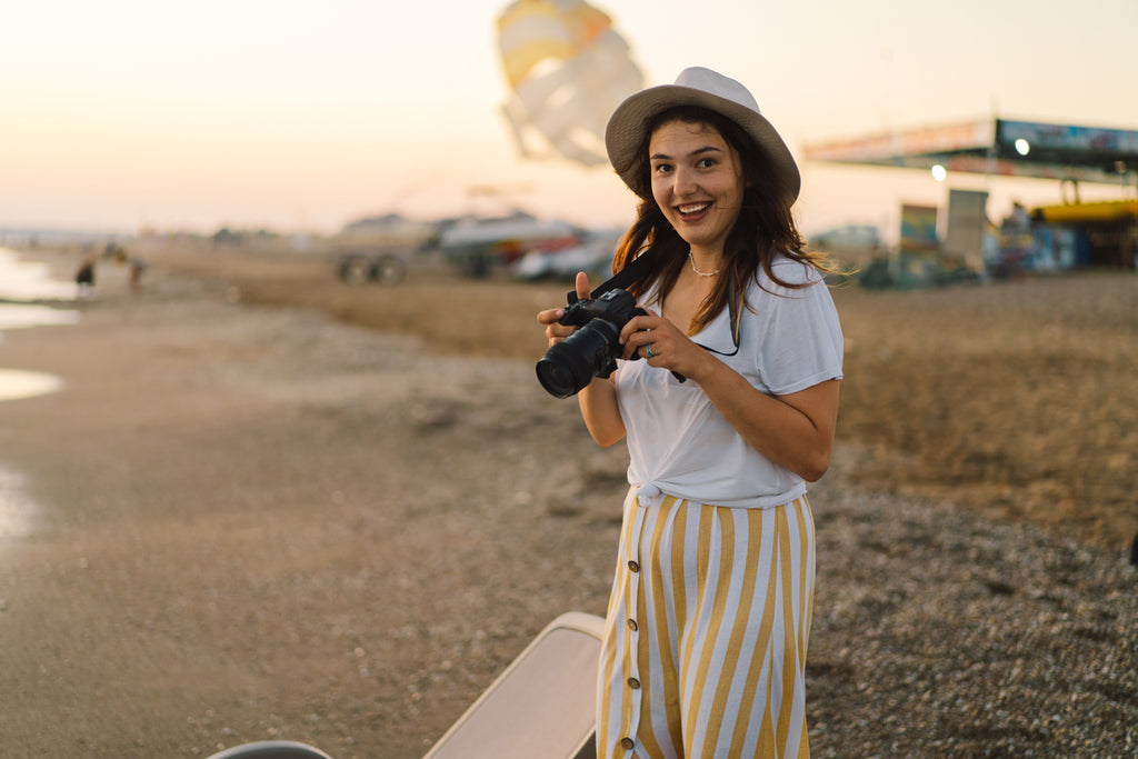Voyage et photographie. Une jeune femme avec un appareil photo est photographiée sur la plage de la mer..