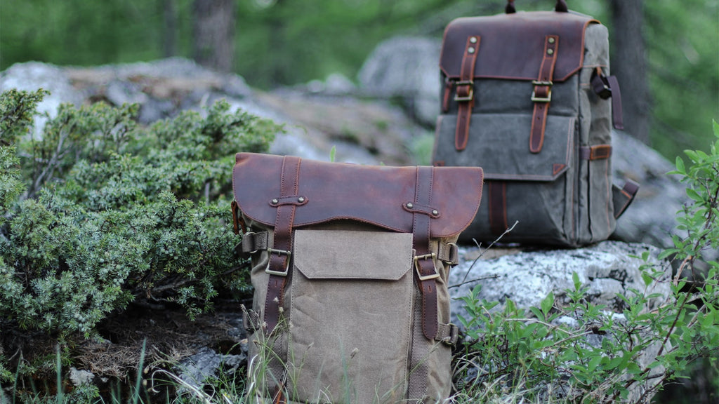 two canvas leather camera backpacks for hiking in a forest