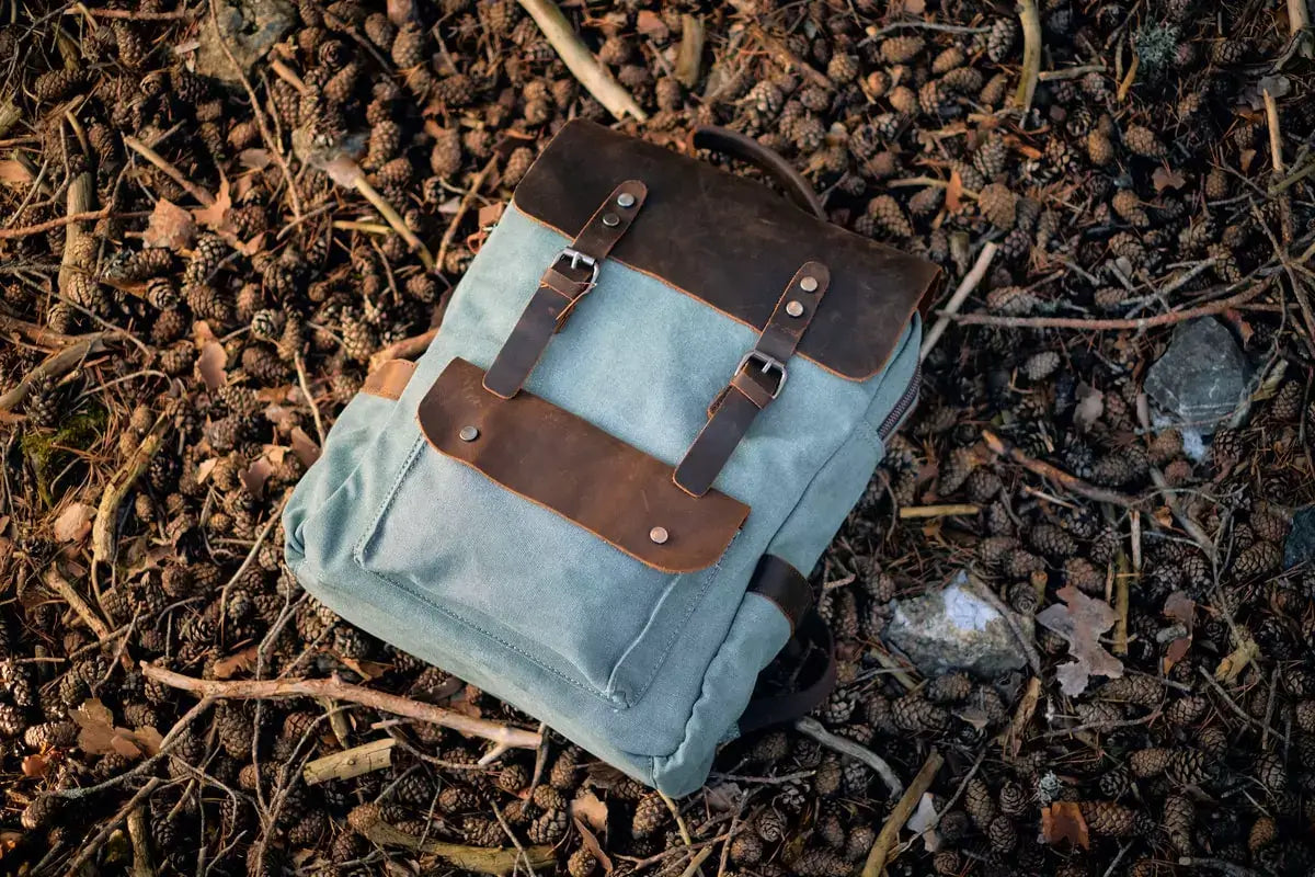 vintage canvas backpack mens laying down the floor with pinecones