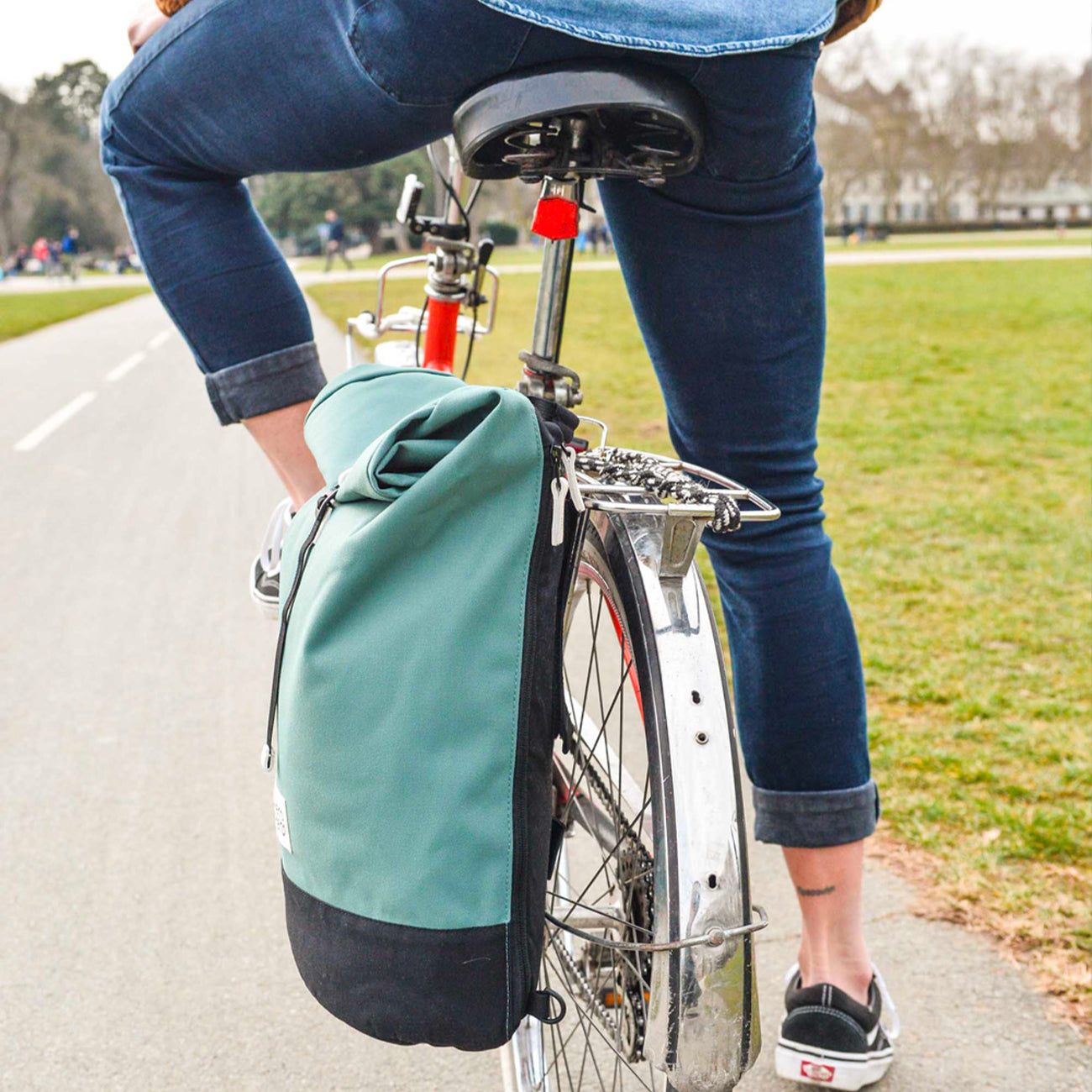 woman riding bike lake blue eco friendly roll top bicycle backpack mero mero