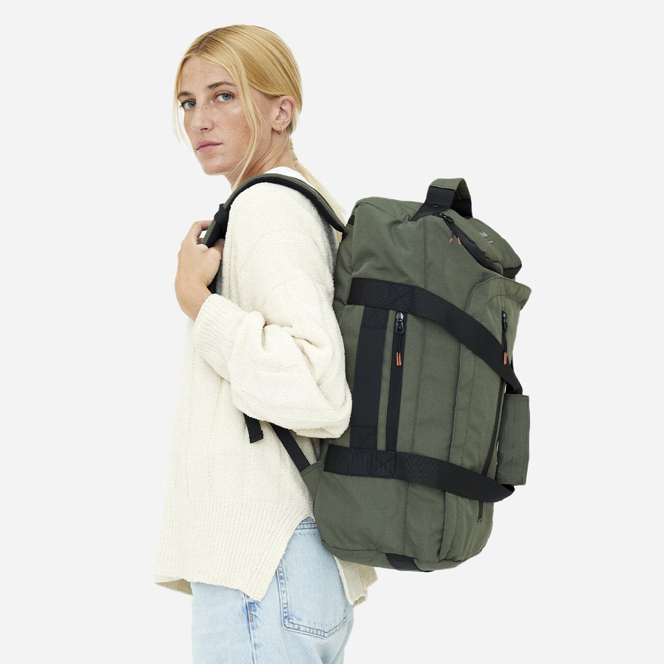Woman wearing green convertible backpack perfect for eco-conscious travelers, side view