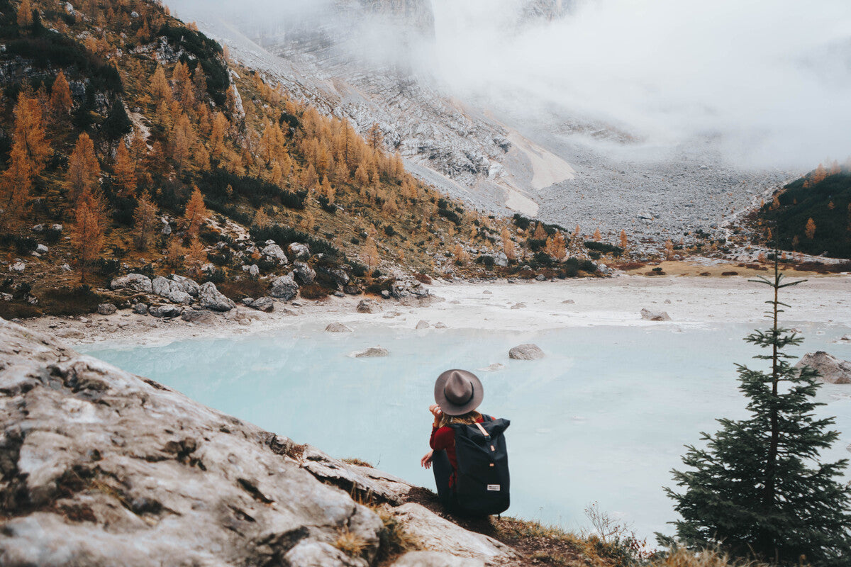 women on a lake deck in annecy rolling her grey roll top recycled bottle backpack