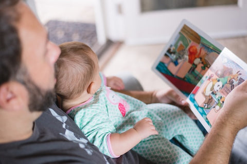 Father holding a baby in his lap and reading them a book