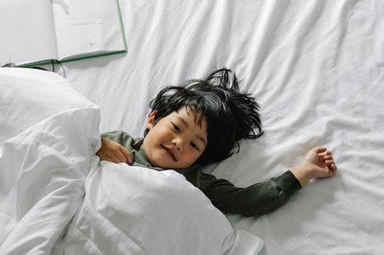 A boy lying in bed after sleep.