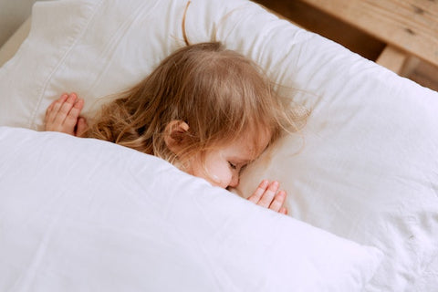 A little girl sleeping on her white cushion represents how vital a sleep schedule is.