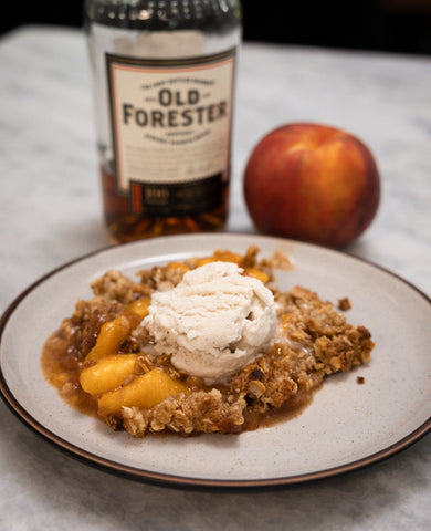 A serving of Bourbon Peach Crisp topped with vanilla ice cream