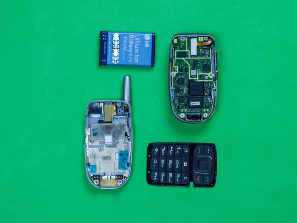 Old cell phone taken apart on green background