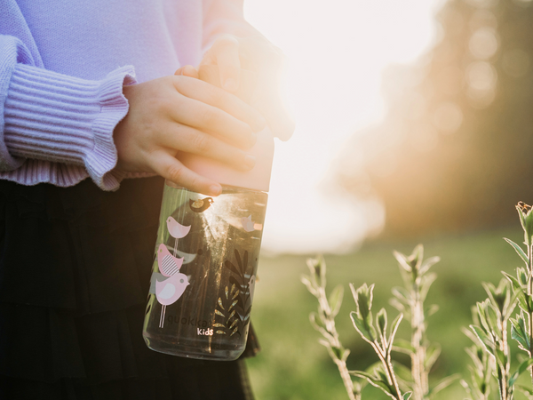 Child holding reusable water bottle in the sun