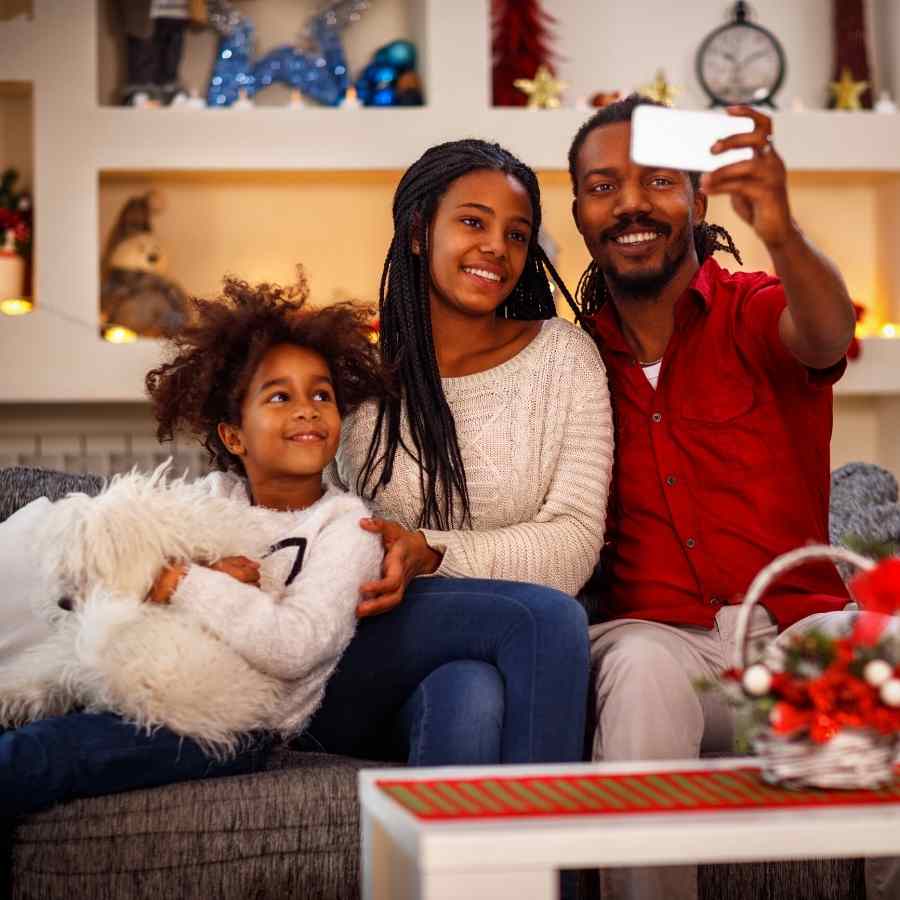 Beautiful black family taking a selfie and celebrating the Christmas holiday with their adorable pup.