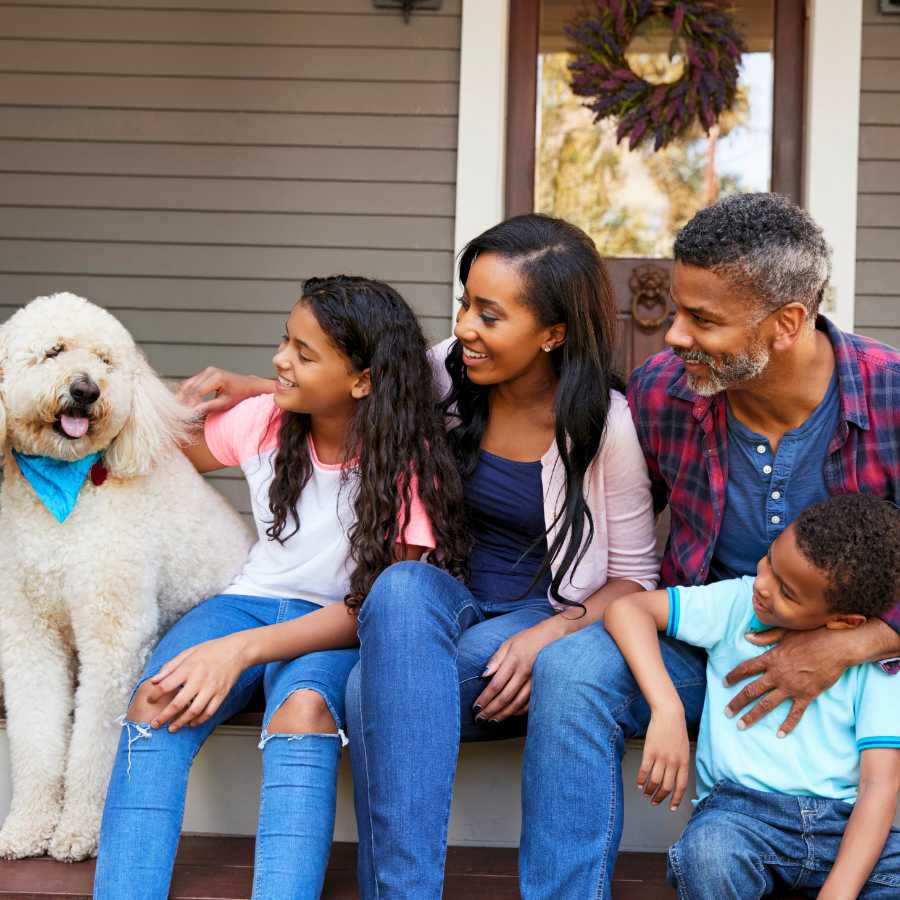 Diverse family sitting on the porch at home with their dog celebrating the Thanksgiving holiday.