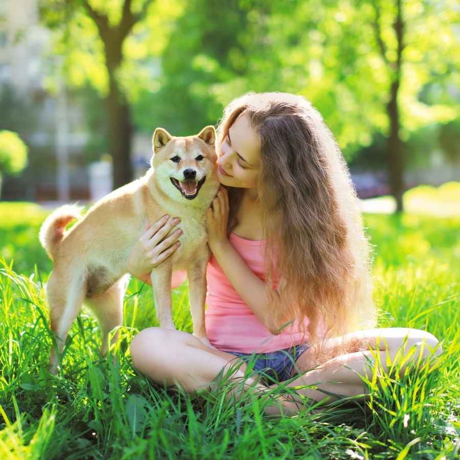 Young woman sitting in the grass with her Shiba Inu, celebrating National Best Friends Day!