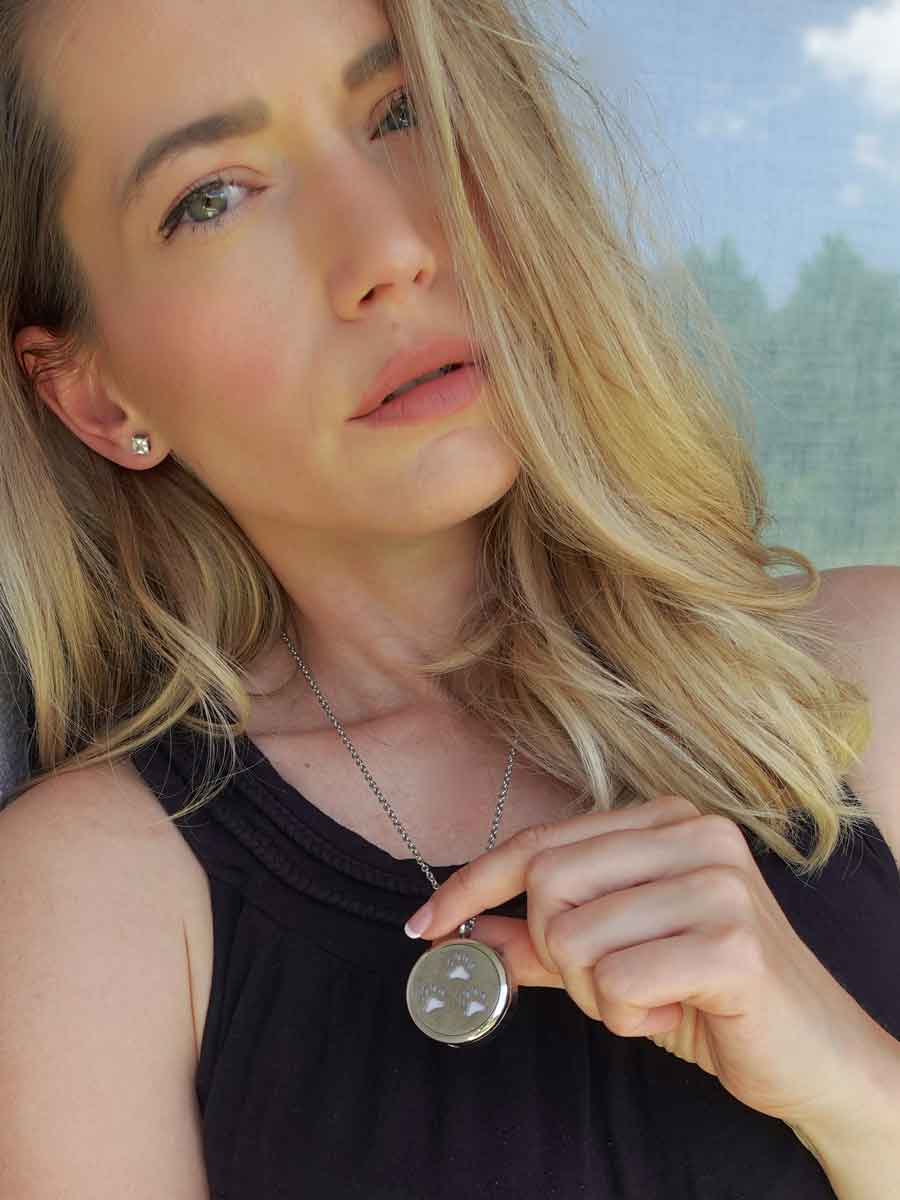 Beautiful young woman holding up the Paw Print Memorial Locket in her hands from online keepsake jewlery shop they made me wear it.