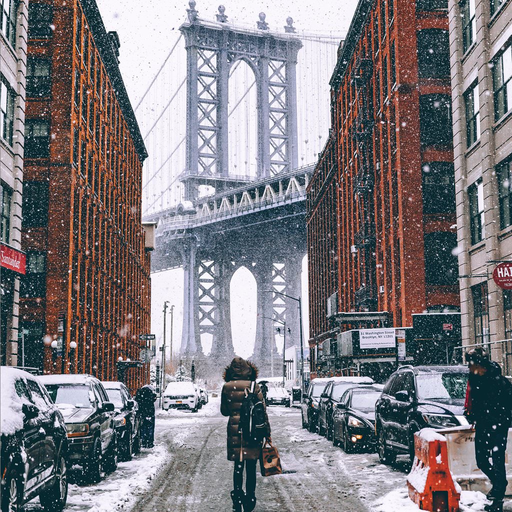Woman in Dumbo looking at Brooklyn Bridge in snow