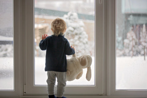 Kind steht vor großem Fenster