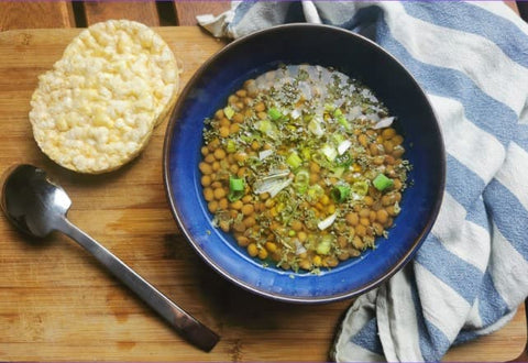 Italian lentil soup in a bowl with rice crackers on a wooden table