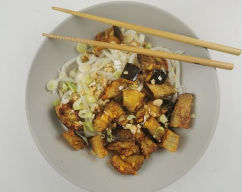 sweet and sour aubergine on a white deep plate and a pair of chopsticks