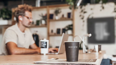 A man sits at the beverage bar with his laptop