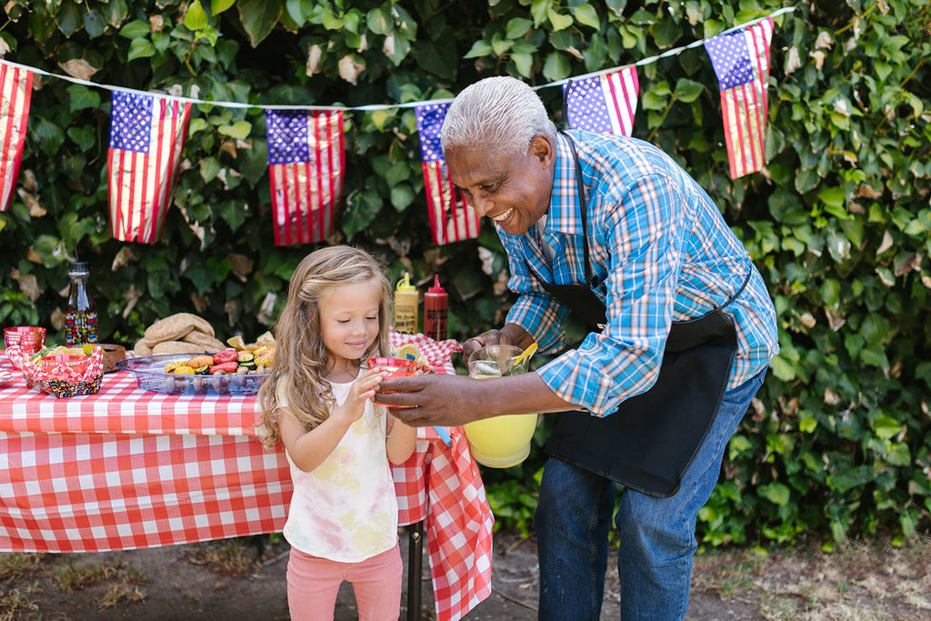 Older man serving a little girl lemonade at a 4th of July BBQ