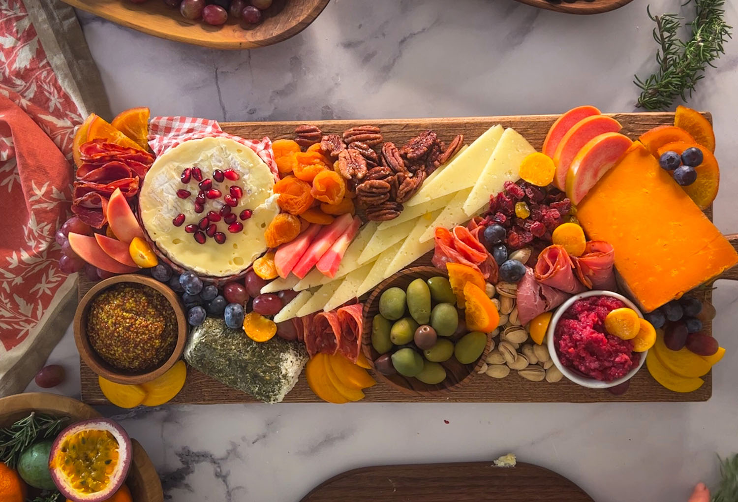 Charcuterie board with dips, olives, grapes, cheeses, folded meats, dried fruits, nuts, and fresh fruit