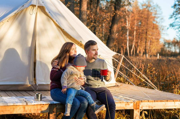family sitting in front of glamping tent