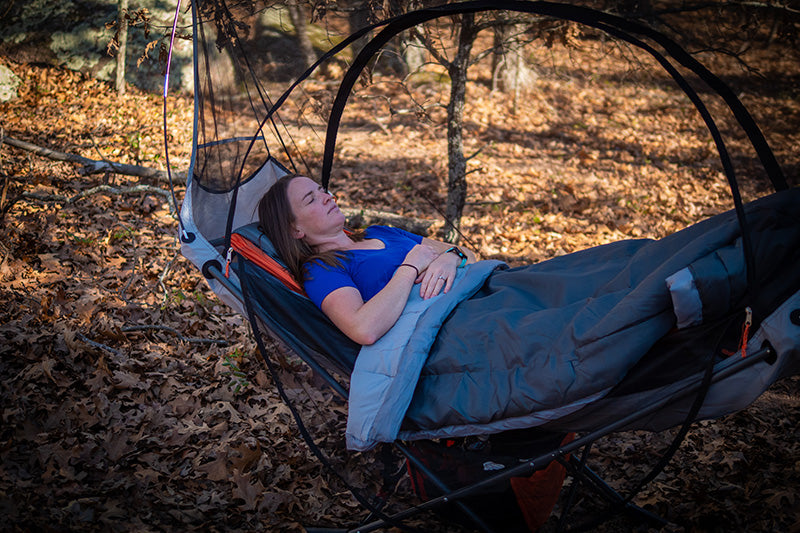 camping in the woods with free  standing hammock and mosquito net