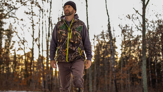 a hunter wears TideWe Men’s Heated Hunting Vest and walks on the snowy ground