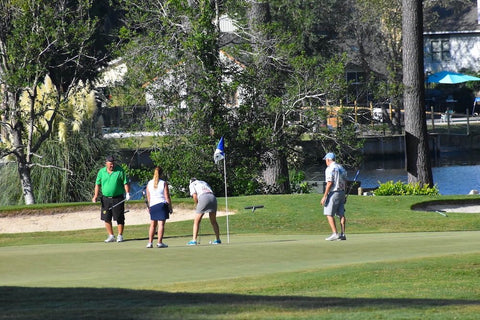 Action shot of a group of golfers on the putting green. 