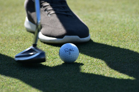 Image of Saintnine golf ball being putt into a hole. 