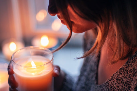 woman from the chest up, holding a lit candle.