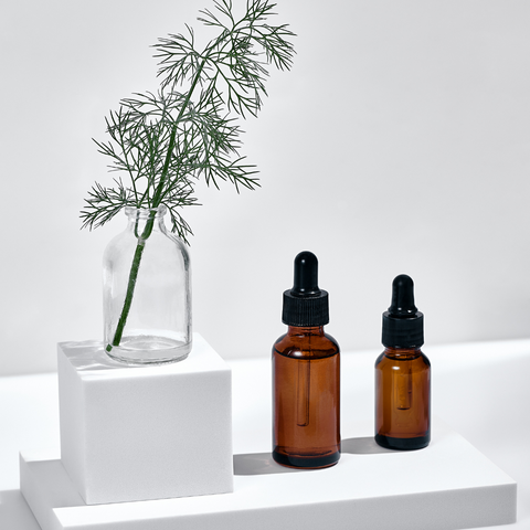 2 bottles of skincare product on plinth with green plants in glass jar