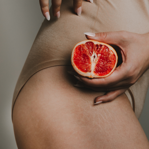 holding pomegranate half near stretch marks on side view leg bottom