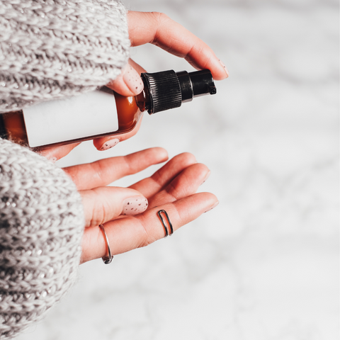 woman pumping bottle of skincare into her hand with wooly jumper