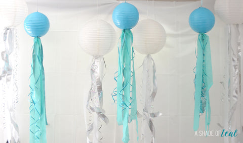 white and teal hanging lanterns with curled streamers hanging down 