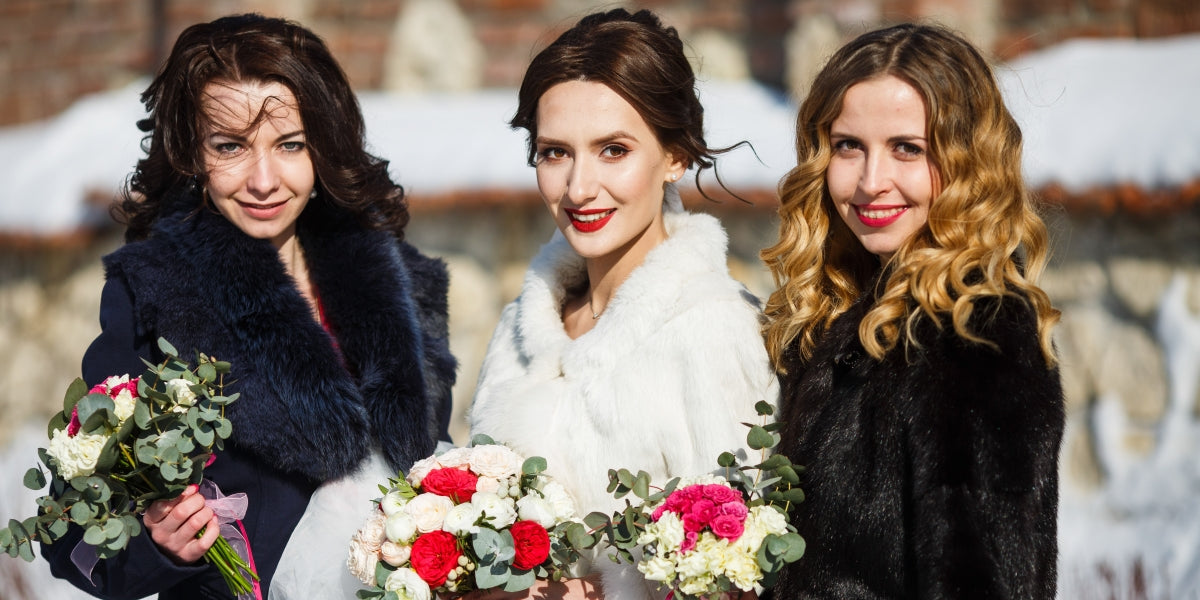 Beautiful bride and bridesmaids in fur coats stand outside in a sunny day