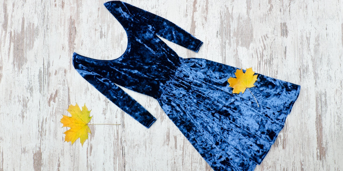 Blue velvet dress and yellow leaves. Fashionable concept.