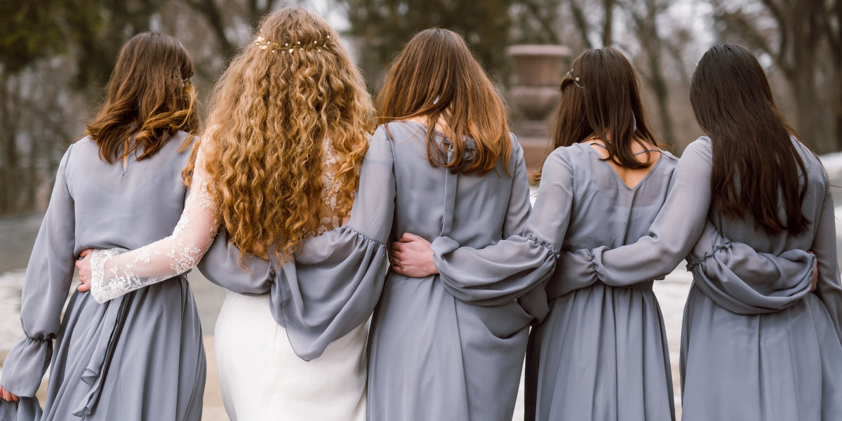 Bride and bridesmaids walking away, wearing gray chiffon dresses.