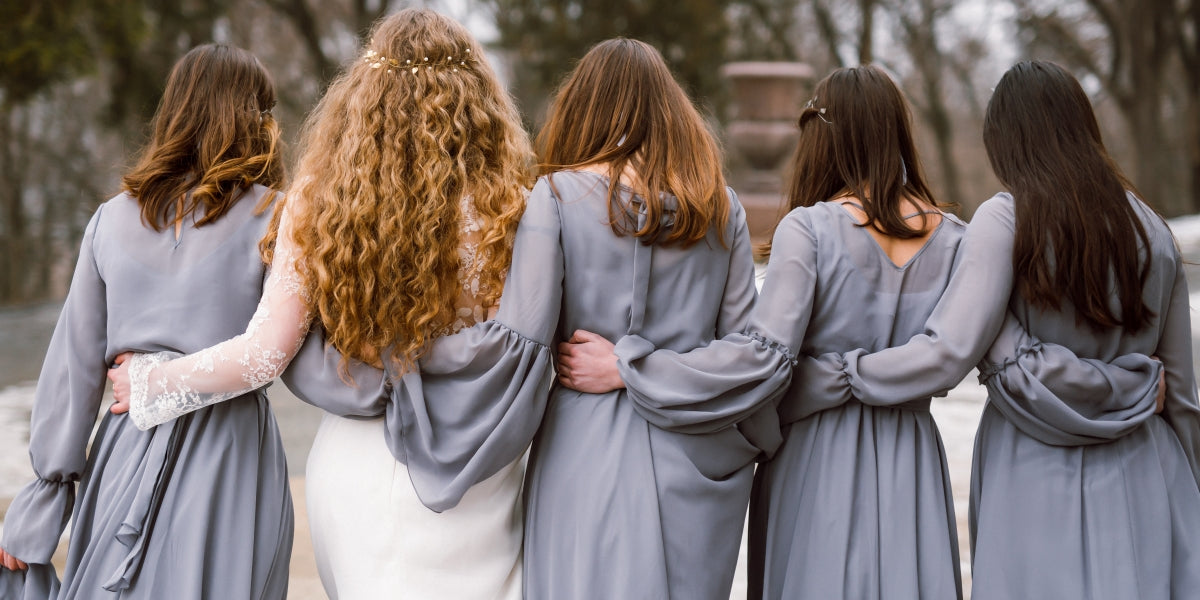 Bride and bridesmaids walking away, wearing gray chiffon dresses.