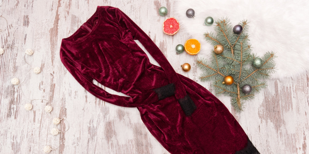 Evening velvet burgundy dress. Halves of citrus and fir branch. Fashionable concept.