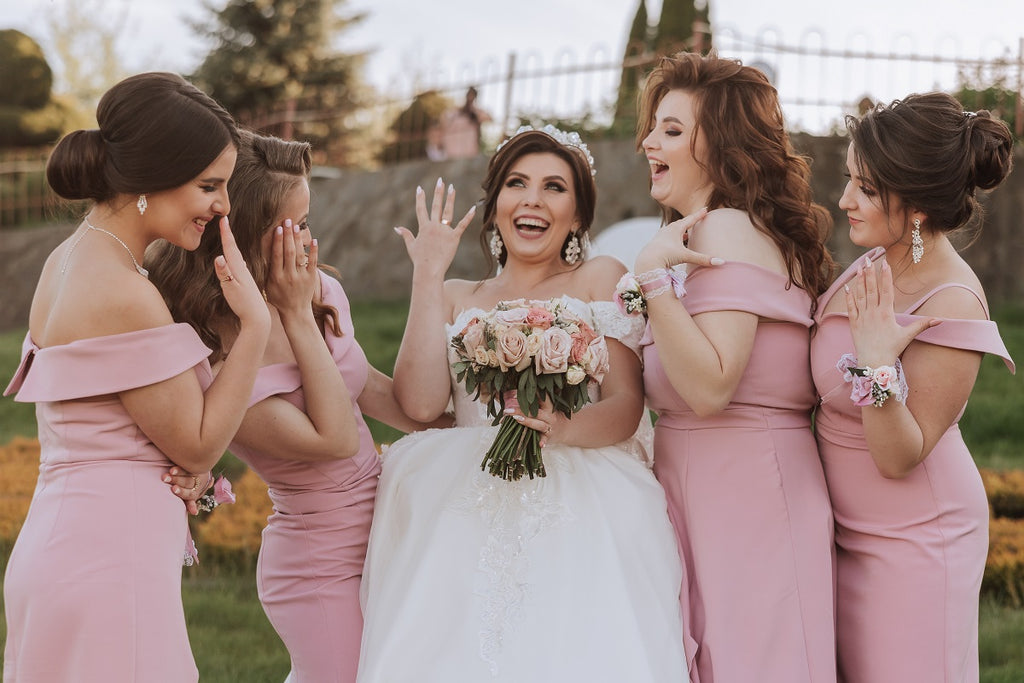 a smiling bride and four bridesmaid in pink dresses