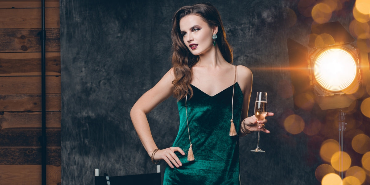 young stylish sexy woman on cinema backstage, celebrating with a glass of champagne, green velvet evening dress, party mood, luxury style, fashion trend