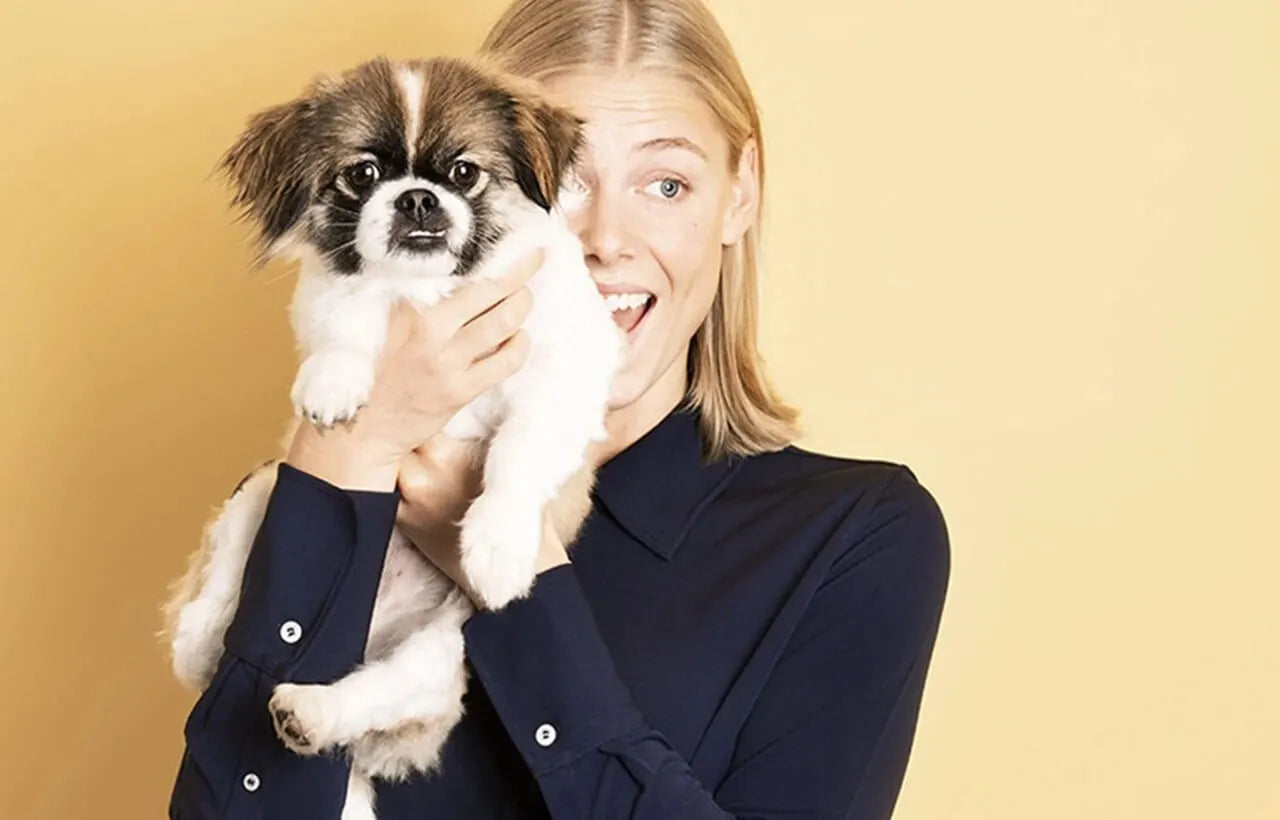 Young woman holding a small dog that might be causing her allergy symptoms