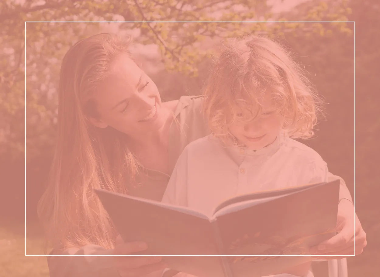 Mother with her young child on her lap, happily reading a book together outside. His hay fever is under control today.