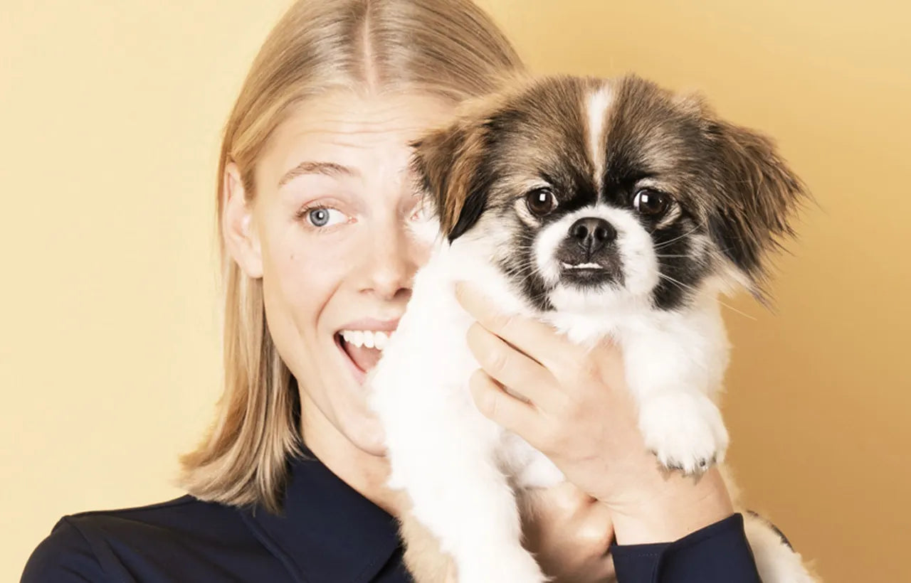 Young woman holding a small dog that might be causing her allergy symptoms