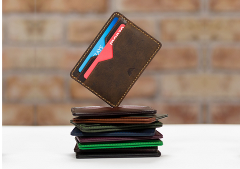Leather card holders piled on top of each other, with the top one face outwards balancing on one corner