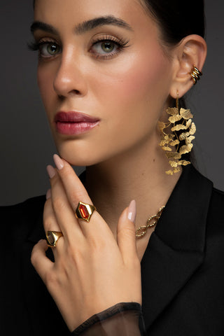 Mujer usando unos aretes grandes y llamativos y anillos de oro