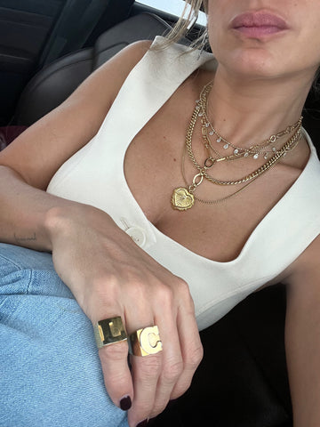 Mujer con top blanco con collar de corazón y dos anillos personalizados con iniciales